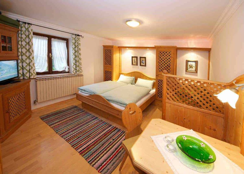 Gemütliches Doppelzimmer im Forsthaus Pernthaner mit Holzdekor und TV, ideal für den Urlaub.