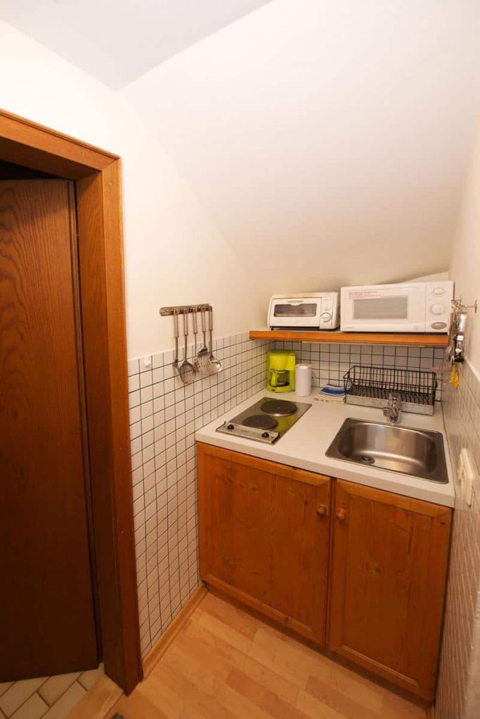 Kleine Küchenzeile mit Spüle, Herd und Mikrowelle in der Privatpension Forsthaus Pernthaner.