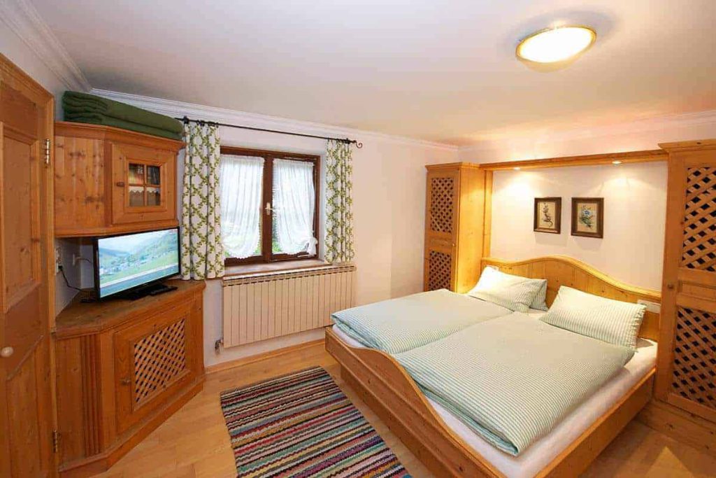 Gemütliches Doppelzimmer im Forsthaus Pernthaner mit TV und holzverzierten Möbeln.