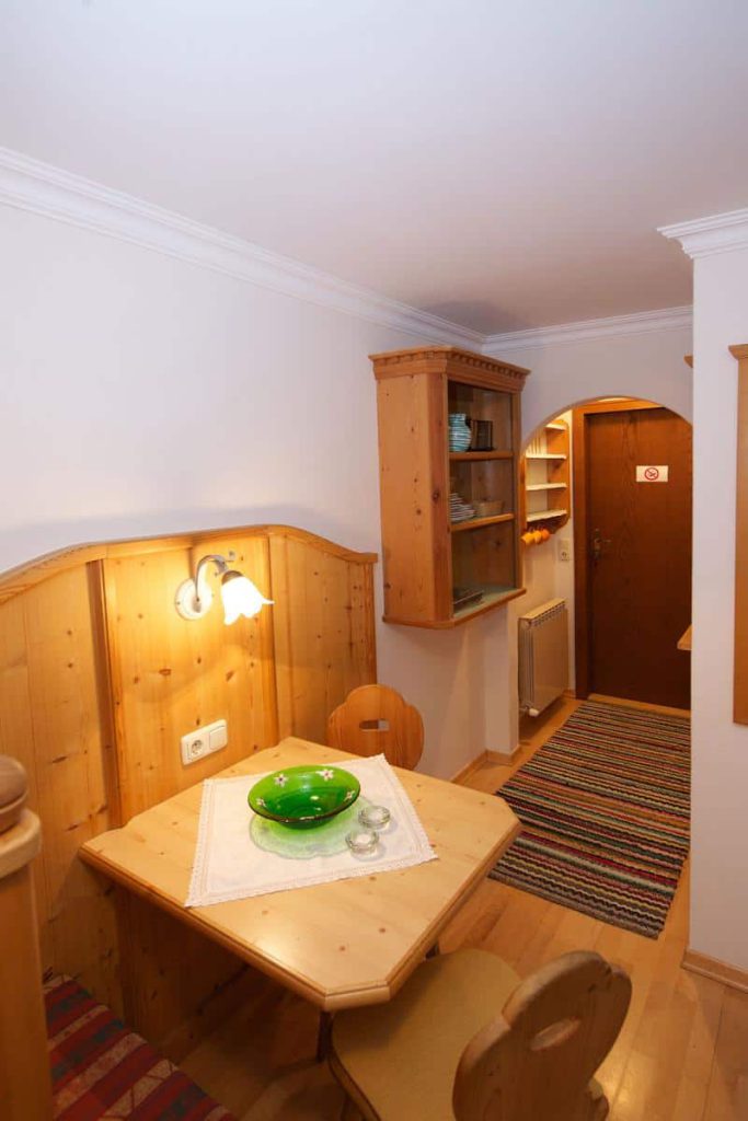 Gemütlicher Essbereich in Holzoptik mit Tisch und grüner Schale im Forsthaus Pernthaner.